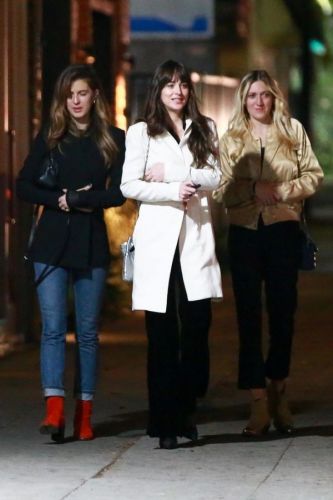 Dakota Johnson in a white coat walks with her friends
